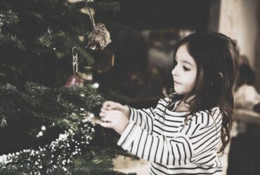 Young girl putting a decoration on a Christmas tree