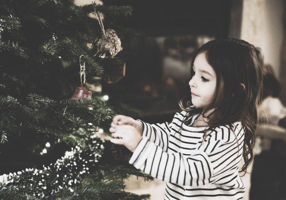 Young girl putting a decoration on a Christmas tree