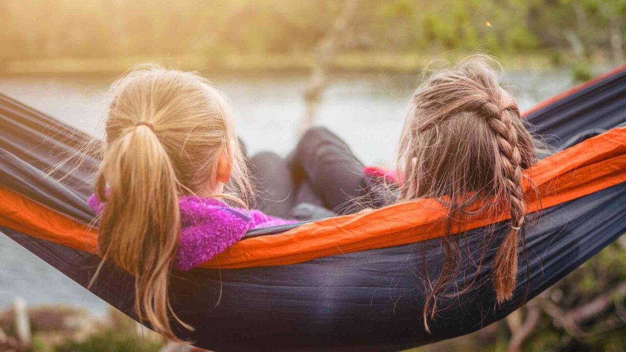 Two girls sitting on a hammock - manage grief over summer holidays - Photo by SI Janko Ferlic on Unsplash