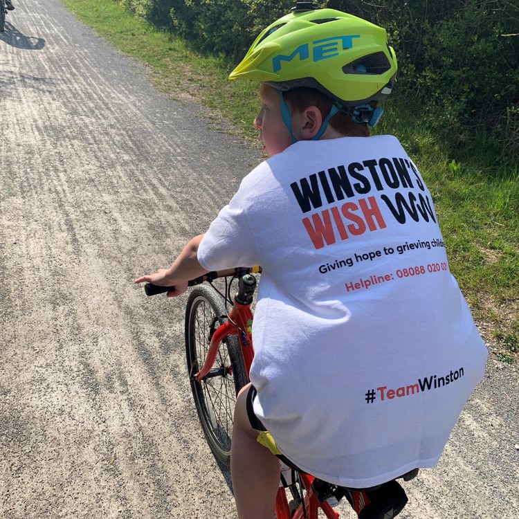 Young boy cycling in a Winston's Wish t-shirt
