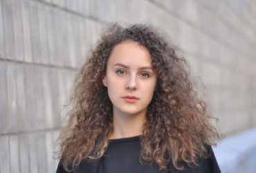 Young woman with curly hair looking at camera