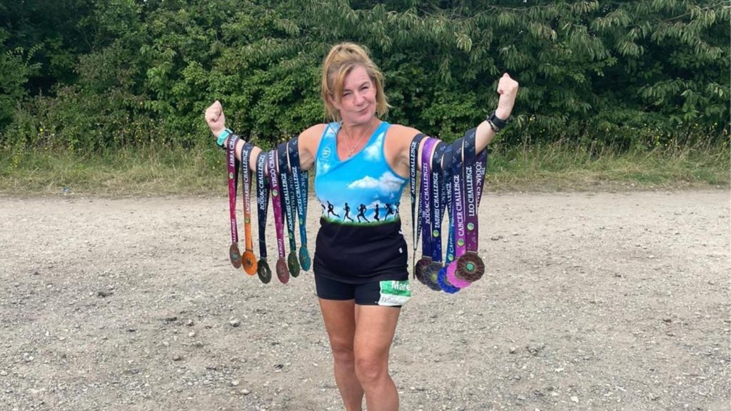marie debont-booth holding up some of her medals from running 100 marathons for winston's wish