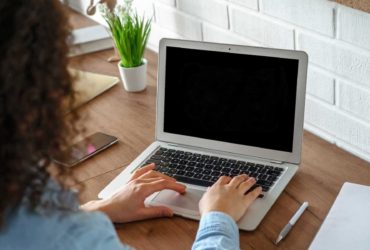 Woman sat at a desk looking at a laptop