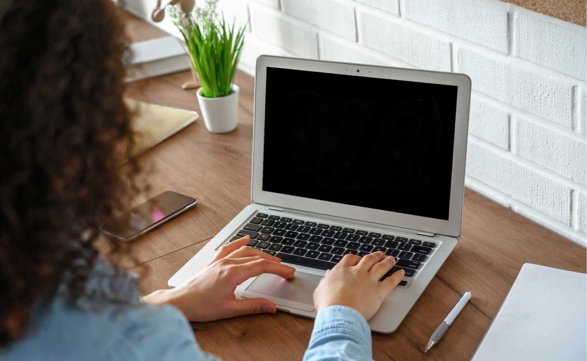 Woman sat at a desk looking at a laptop