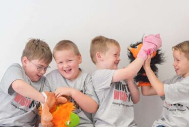 Four young boys in Winston's Wish t-shirts playing with puppets