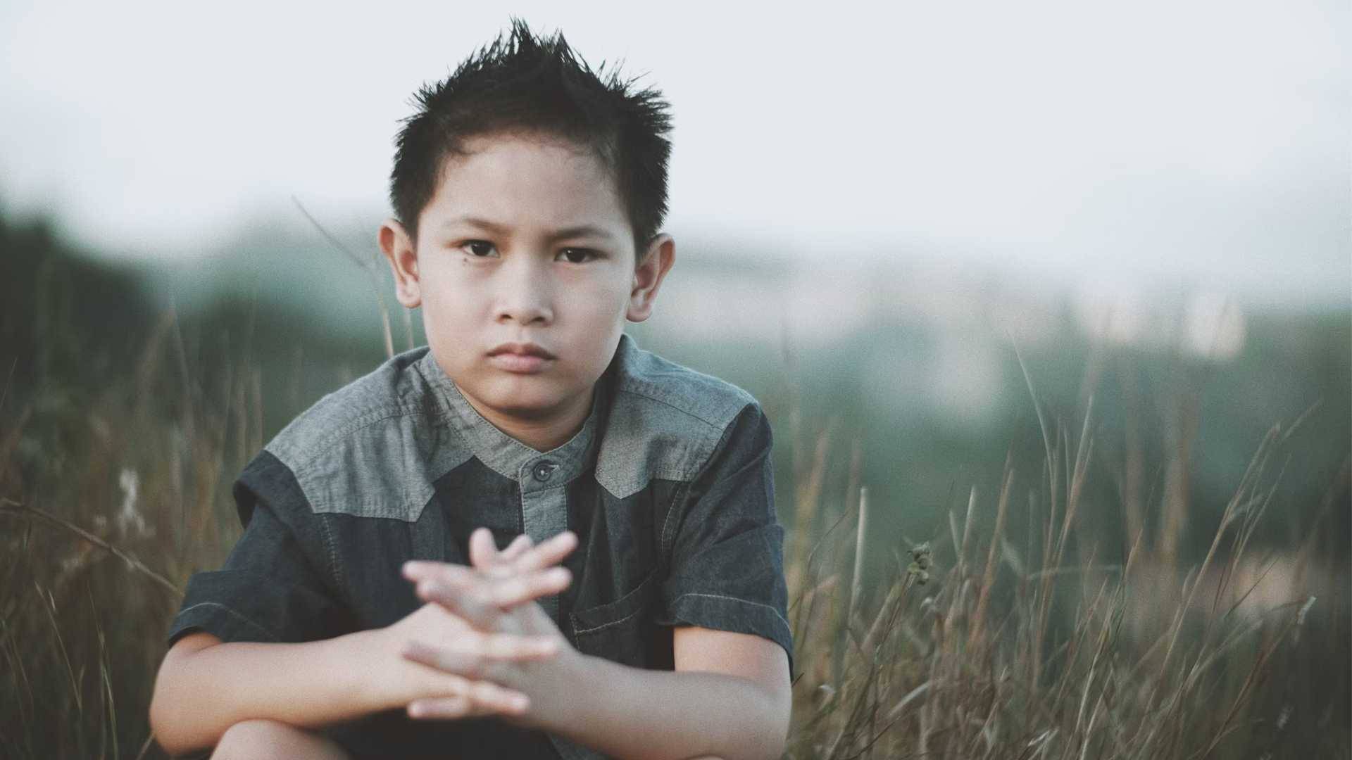 Young boy crouching in a field