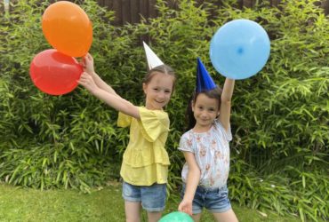 Two young girls with balloons and party hats celebrating Winston's Wish 30th birthday