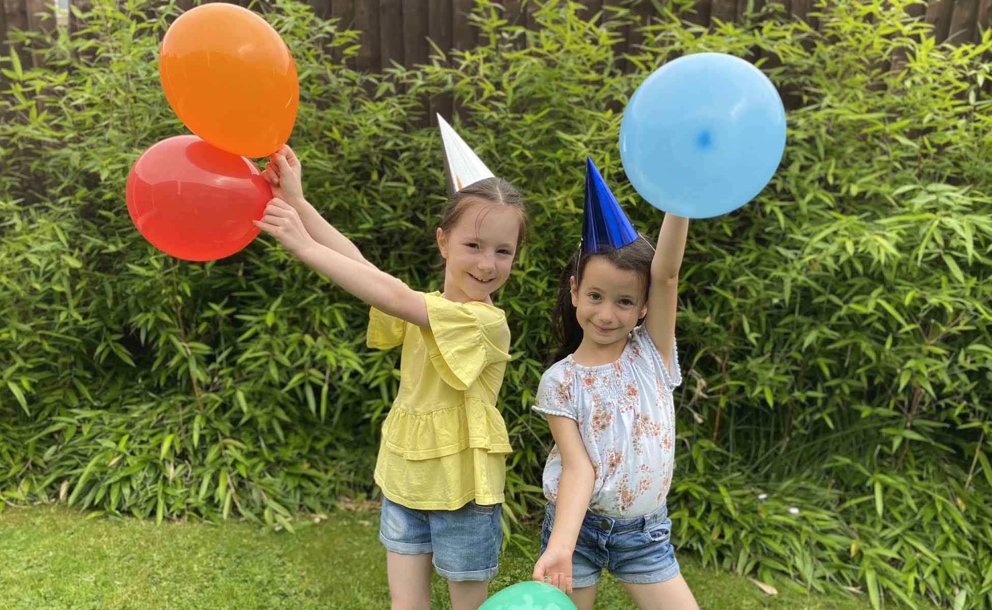 Two young girls with balloons and party hats celebrating Winston's Wish 30th birthday