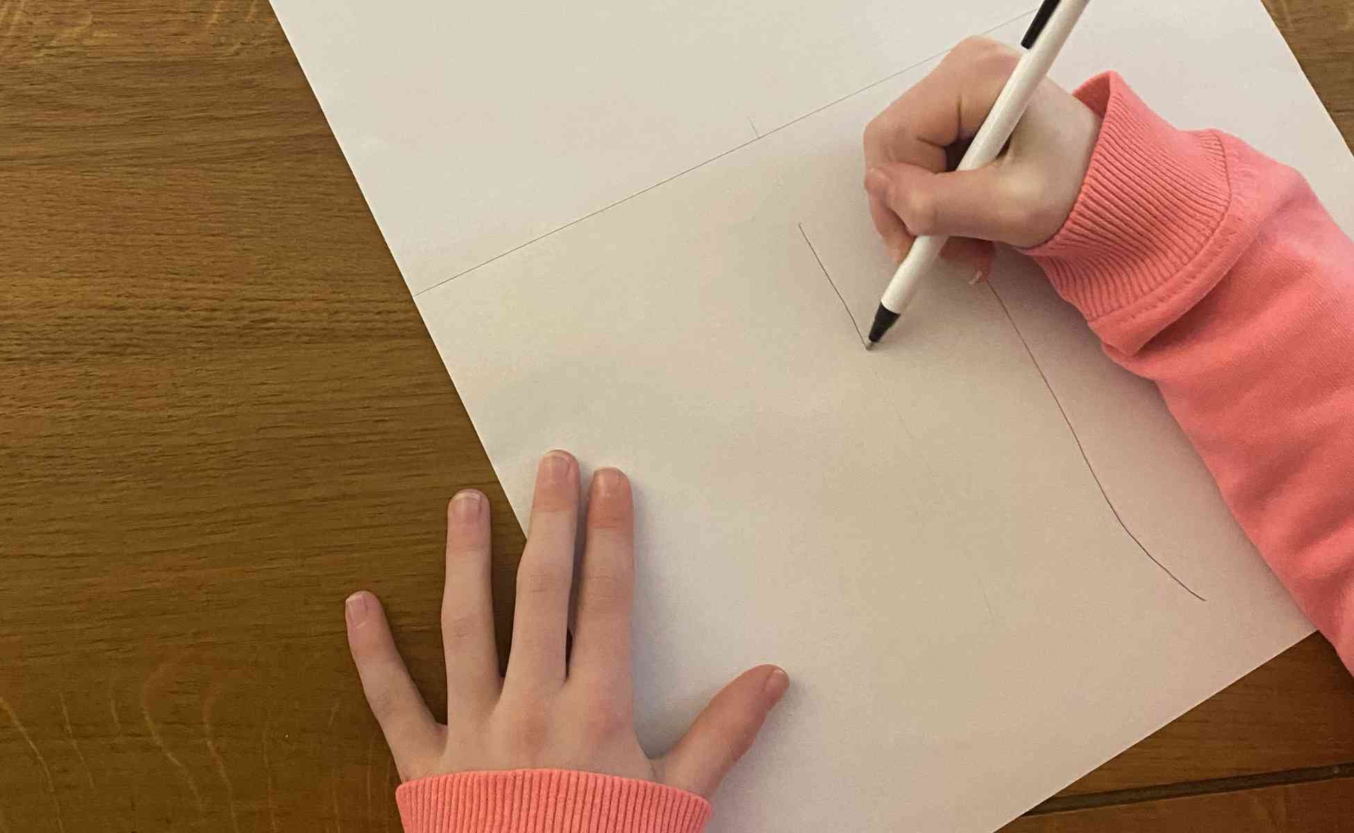 Photo of a child drawing a tree trunk on paper - Thankful tree activity, step 2