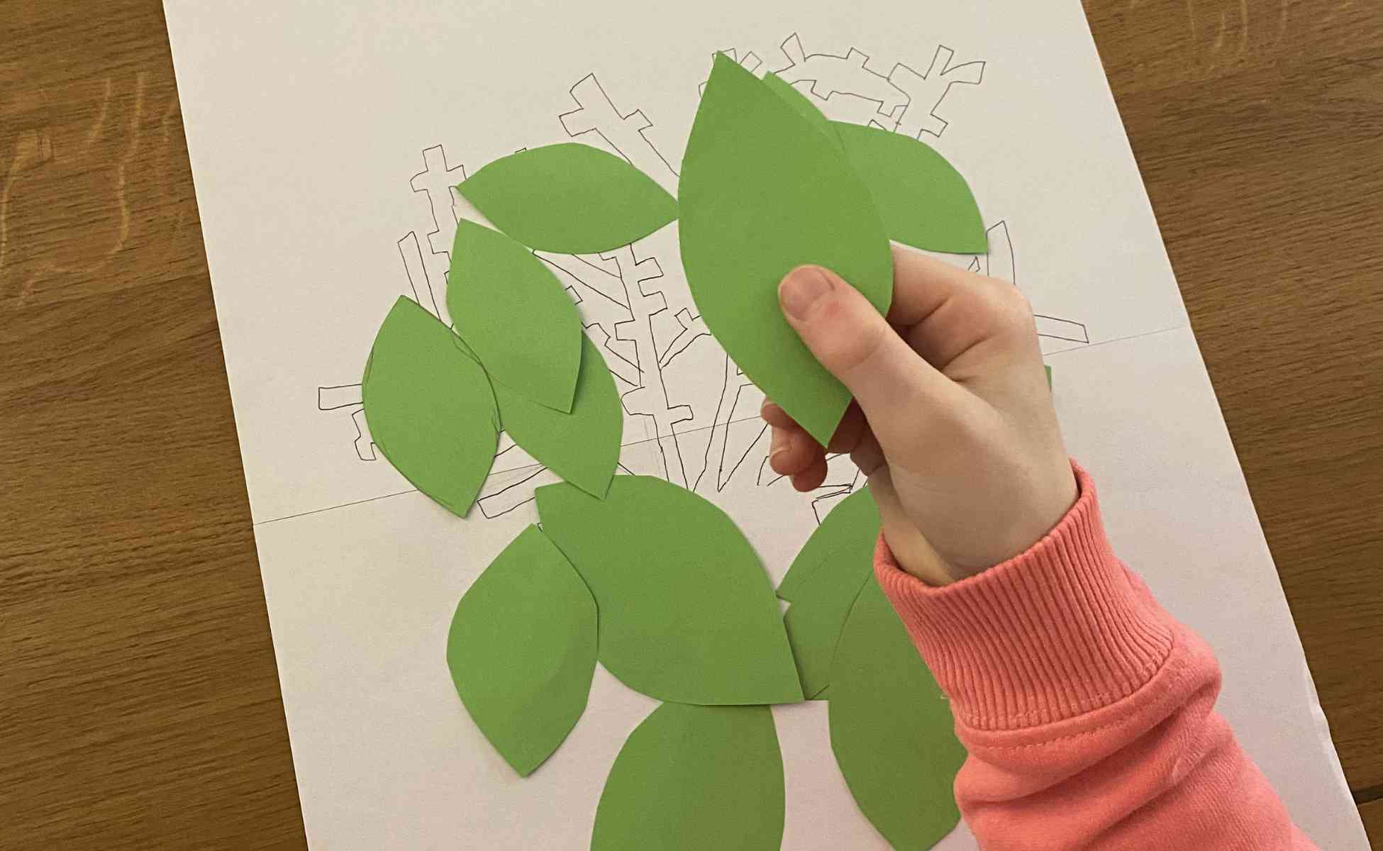 Photo of child's hand holding a leaf shape cut from green paper - Thankful tree, step 4