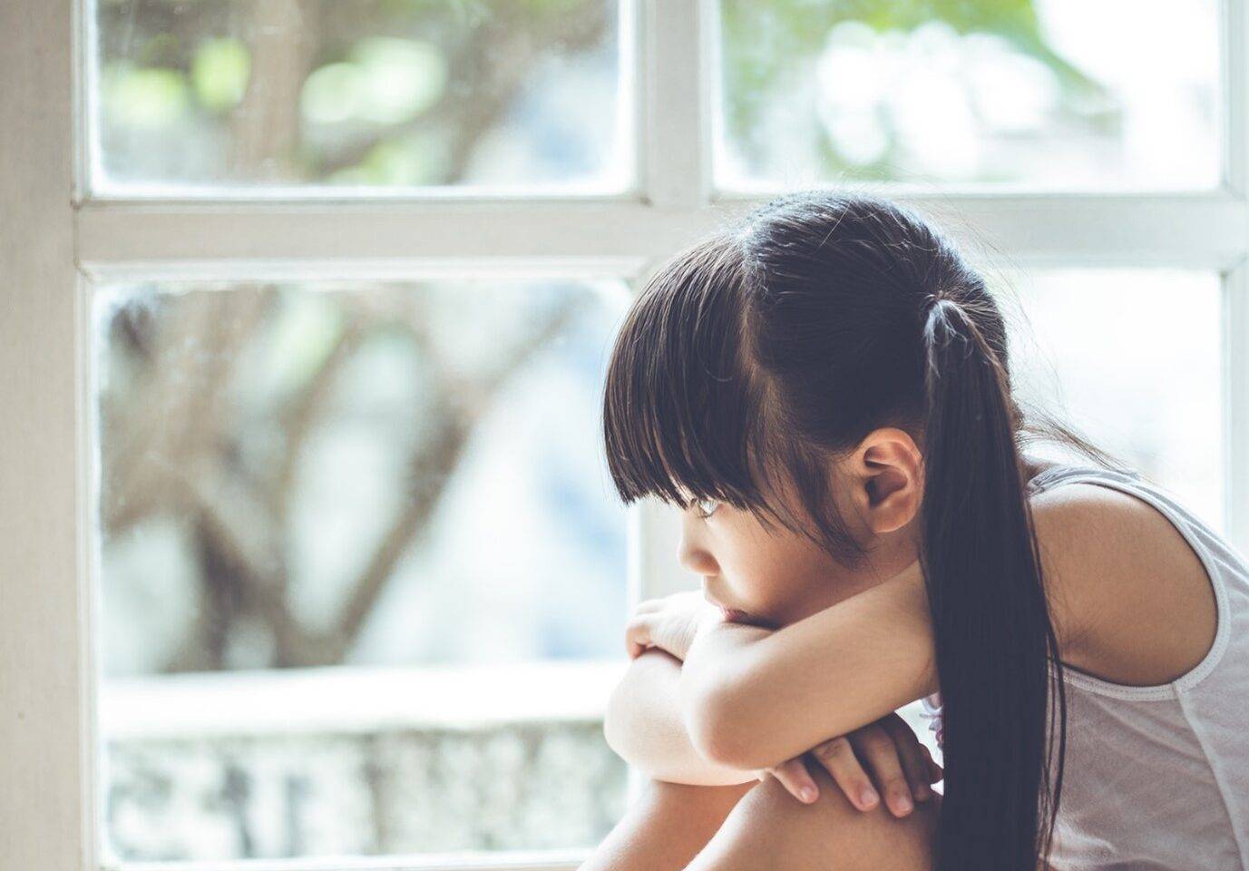 Photo of a young girl looking out of a window