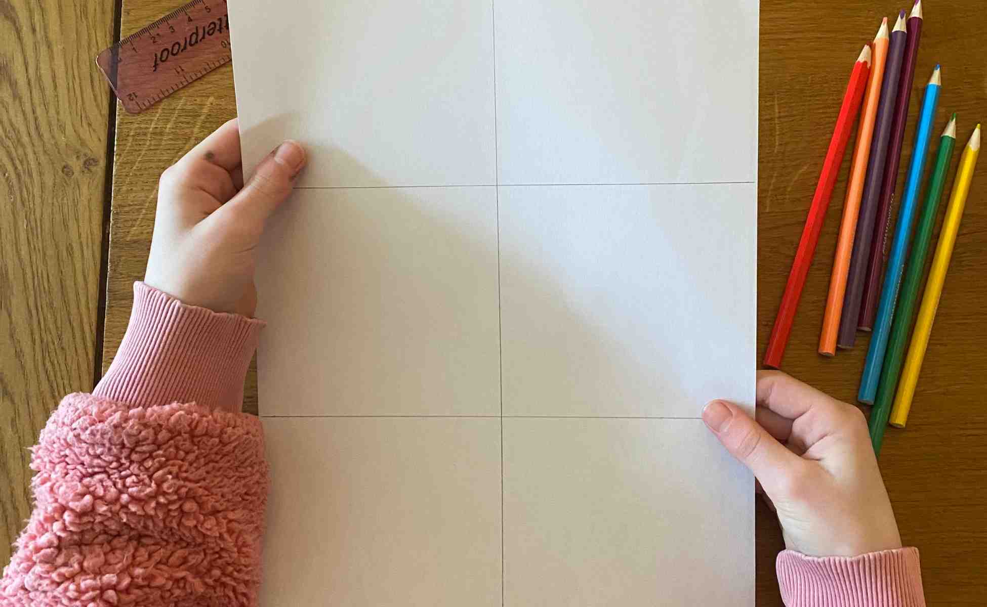 Photo of a child's hands holding a piece of paper divided into a grief of six boxes - Winston's wish Rainbow Review activity, step 1