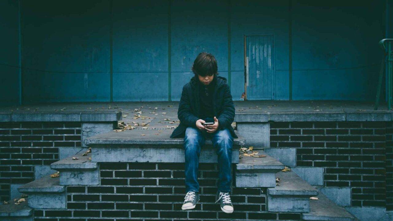 Photo of a teenage boy sat on a wall