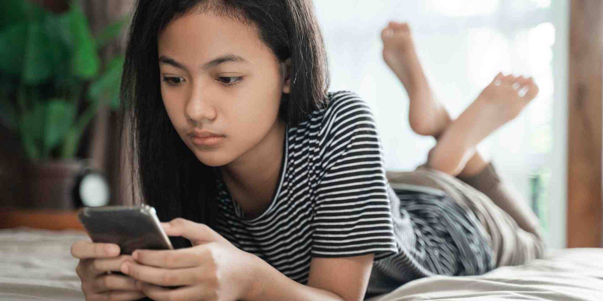 Teenage girl lying down and using a phone - Winston's Wish summer services