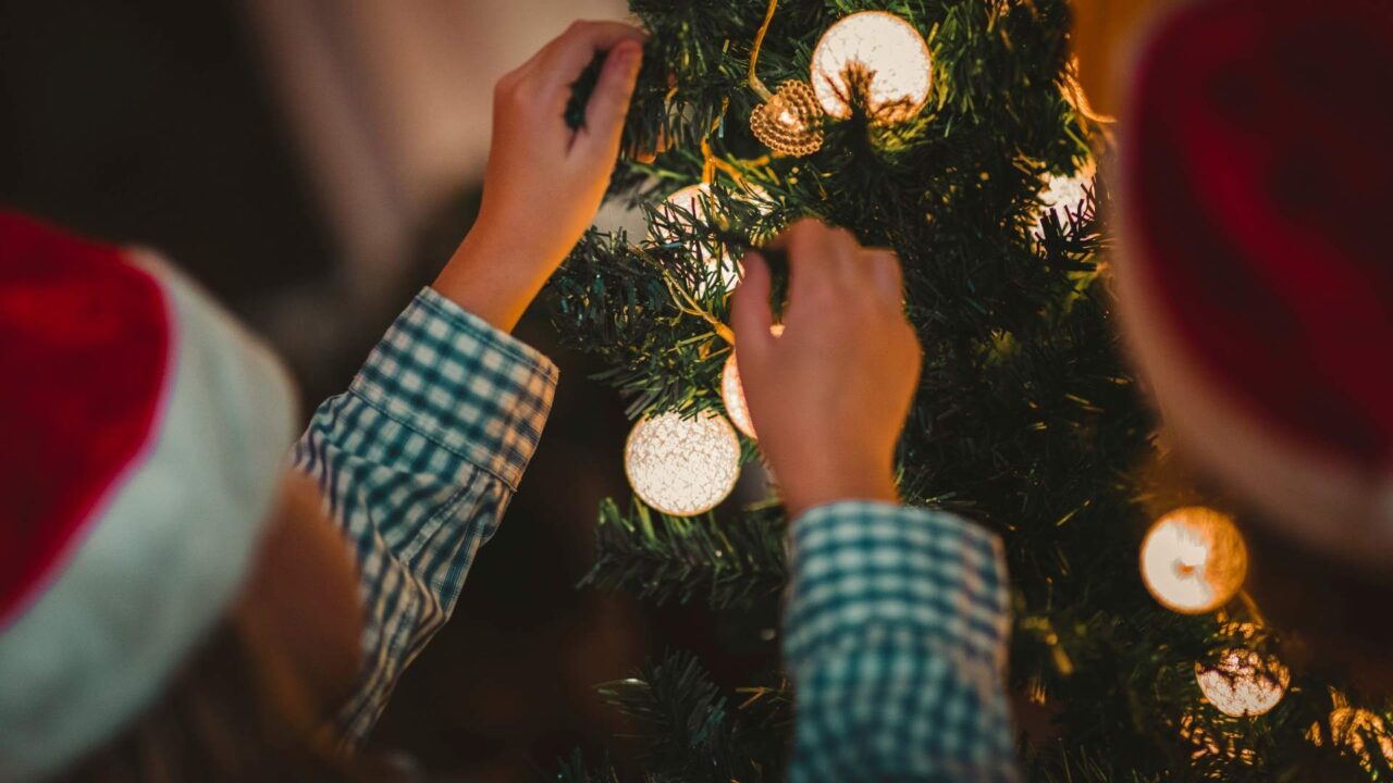 Child's hands decorating a Christmas tree