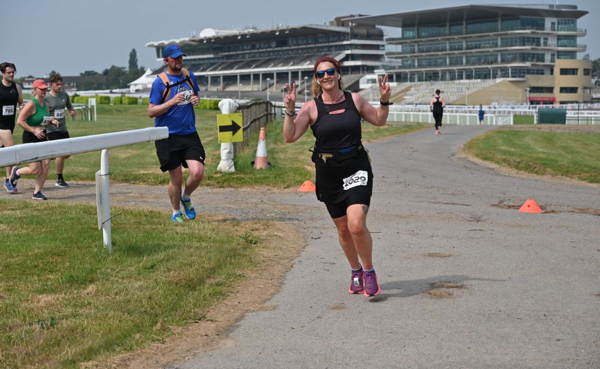 Runner at the Cheltenham Running Festival giving peace signs as she runs
