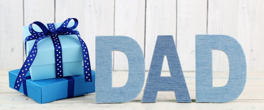 Father's Day image with the word Dad displayed next to presents on a neutral background